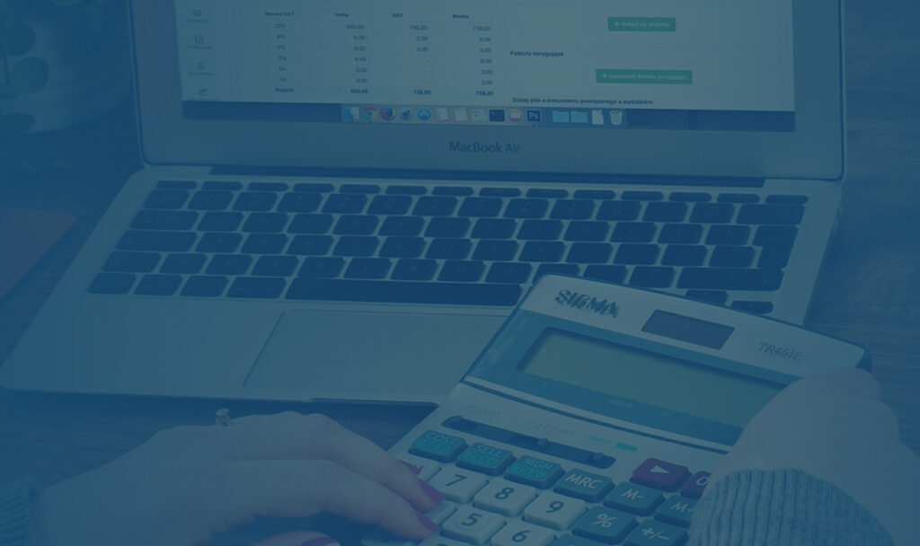 Hands using a calculator beside a laptop spreadsheet while checking helpful links for tax filing